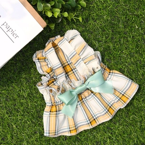 Détail d'une robe pour chien à carreaux jaunes avec grand nœud en satin vert et volants
