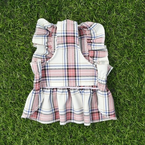 Détail d'une robe à carreaux pour chien avec bretelles à volants sur herbe
