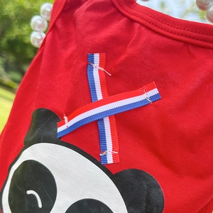 Détail de la veste rouge pour animaux avec ruban tricolore et motif panda mignon