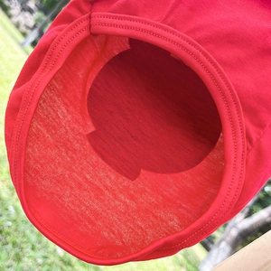 Détail du gilet en maille rouge pour chien montrant les bords côtelés sur l'herbe