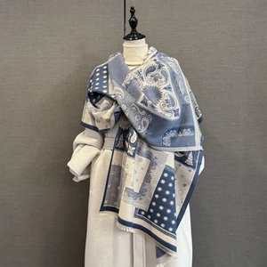 Detail of blue paisley pattern pashmina scarf with fringe edge on a white coat