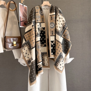 Detail of paisley pashmina shawl with fringes styled over a white autumn coat