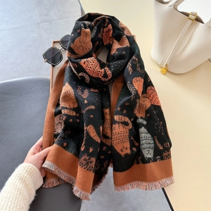 Detail of soft cashmere-like scarf with cat patterns and fine tassel edges in black and orange
