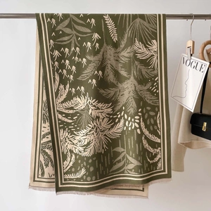 Dettaglio scialle in maglia a tema foresta con stampa di palme e nappine a frangia