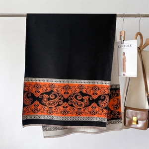 Detail of the reversible paisley cashmere scarf showing orange pattern and soft tassels