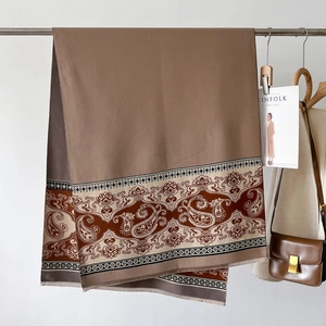 Detail of soft cashmere-like scarf showing paisley pattern, fringe, and camel texture