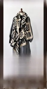 Dettaglio di una spessa sciarpa in finto cashmere con motivi geometrici e frange bordate