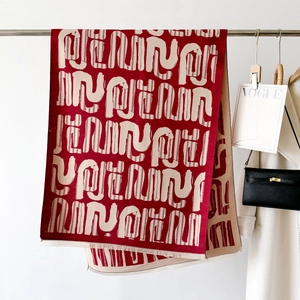 Dettaglio della sciarpa rosso scuro con motivo jacquard astratto e frange fini