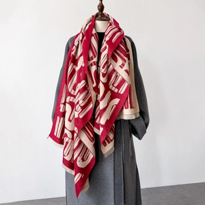 Dettaglio dello scialle lavorato a maglia rosso e beige con motivi geometrici