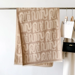 Dettaglio di scialle pashmina beige con morbide frange e motivi artistici astratti