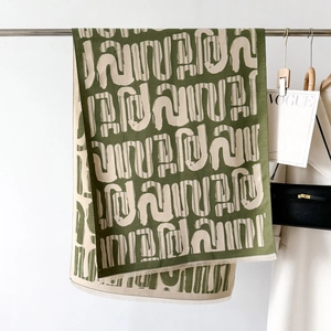 Dettaglio ravvicinato della sciarpa jacquard oliva e beige con bordi sfrangiati