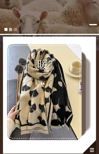 Detail of beige scarf with black ginkgo leaf pattern and delicate soft tassels
