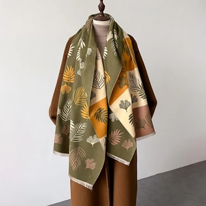 Detail of multi-color leaf print shawl scarf with fine tassel fringe on soft fabric