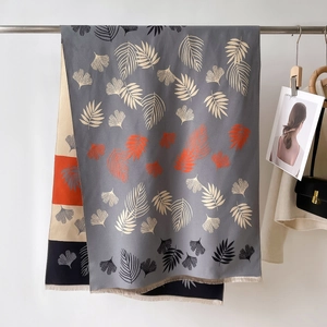 Close-up of thick winter scarf with leaf print and delicate fringe tassels