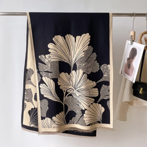 Detail of thick black scarf with golden ginkgo leaf prints and fine fringe edges