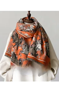 Détail du châle orange luxueux montrant des motifs de chevaux et des bords à franges