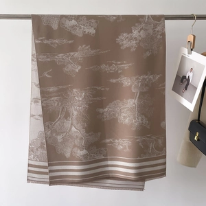 Detail of printed scarf with landscape pattern and fringe hanging on metal rod