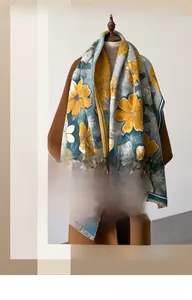 Gros plan sur châle floral à base grise, fleurs jaunes et bordures à pompons doux