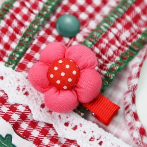 Detailed macro view of handmade pink floral pet hair clip with red polka dot center accent