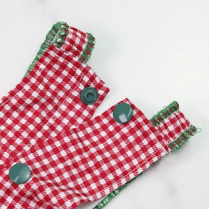 Detail of red houndstooth pet dress with green snap buttons and edge stitching