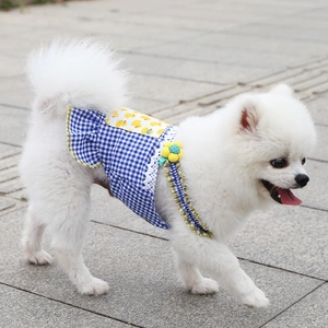 Close-up of blue plaid pet dress with yellow duck patch and lace trim on a white dog