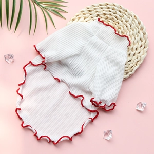 Détail de gilet pour animaux en maille gaufrée avec bords festonnés rouges sur rose