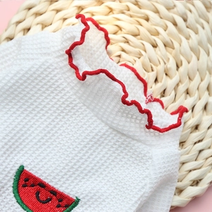 Détail macro du t-shirt blanc gaufré pour animaux avec volants rouges et broderie pastèque