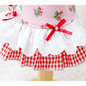 Détail de robe pour animal avec imprimé fleuri, dentelle et nœud en soie rouge à perle