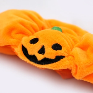 Detail of soft plush pumpkin headband for pets with embroidered Jack-o'-lantern face