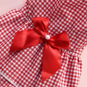 Detail of red checkered dog dress featuring a large satin bow with a pearl center