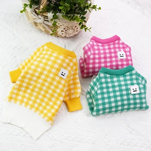 Close-up of plaid pet sweaters in yellow, pink and green with soft knitted textures