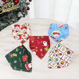 Flat lay of five Christmas dog bandanas with festive prints on white marble table