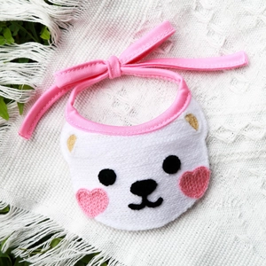 Close-up of white knitted pet bib with cute bear embroidery and pink ribbons