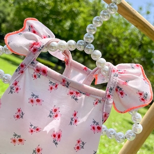 Robe rose à fleurs pour animaux avec bretelles à volants sur cintre dans un jardin