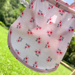 Détail de la robe rose à fleurs pour chien avec lanière en perles sur fond naturel