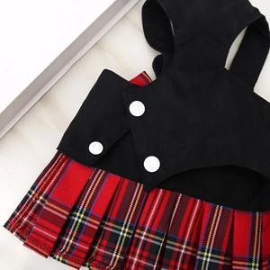 Detalle de vestido para perro con chaleco negro, botones blancos y falda plisada de cuadros