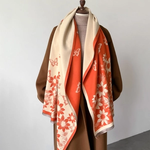 Vintage floral and butterfly shawl in orange and beige with fringe, draped on coat