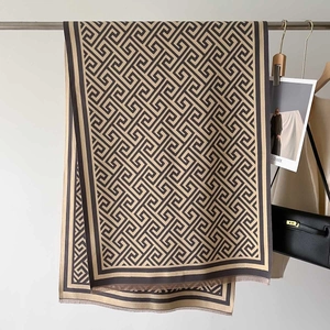 Detail of a thick cashmere-style scarf with black and brown geometric maze patterns and fringes
