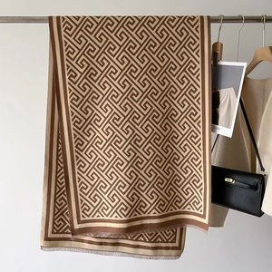 Detail of soft geometric pattern knit scarf with fringe trim and hanging drape