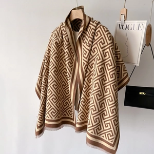 Thick geometric knit scarf in brown and beige with fringe, draped on a hanger