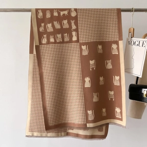 Detail of soft brown knit scarf featuring cartoon cat prints and houndstooth pattern
