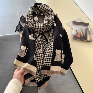 Detail of knitted scarf showing houndstooth cat patterns and soft tassel texture