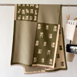 Detail of green and beige scarf with cat illustrations and houndstooth pattern fringe
