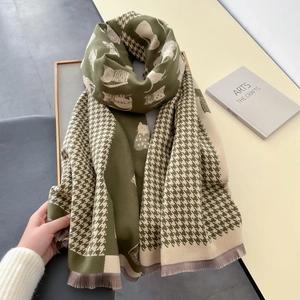 Detail of knit scarf featuring dark green houndstooth pattern and cat silhouette designs