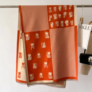 Detailed macro view of houndstooth knit shawl with fringe and cat illustration