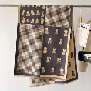 Detail of winter scarf featuring houndstooth pattern and cartoon cat prints with tassels