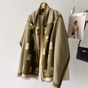 Olive green houndstooth scarf with cat illustration and tassels on a wooden hanger