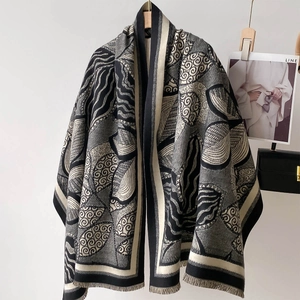 Detail of the thick leaf pattern fringe on a black, grey and cream luxury cashmere shawl