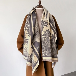 Detail of palm tree print scarf with tassels over a wool coat and sweater
