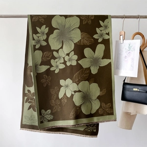 Close-up of floral print scarf with soft tassels hanging on a metal rod for display